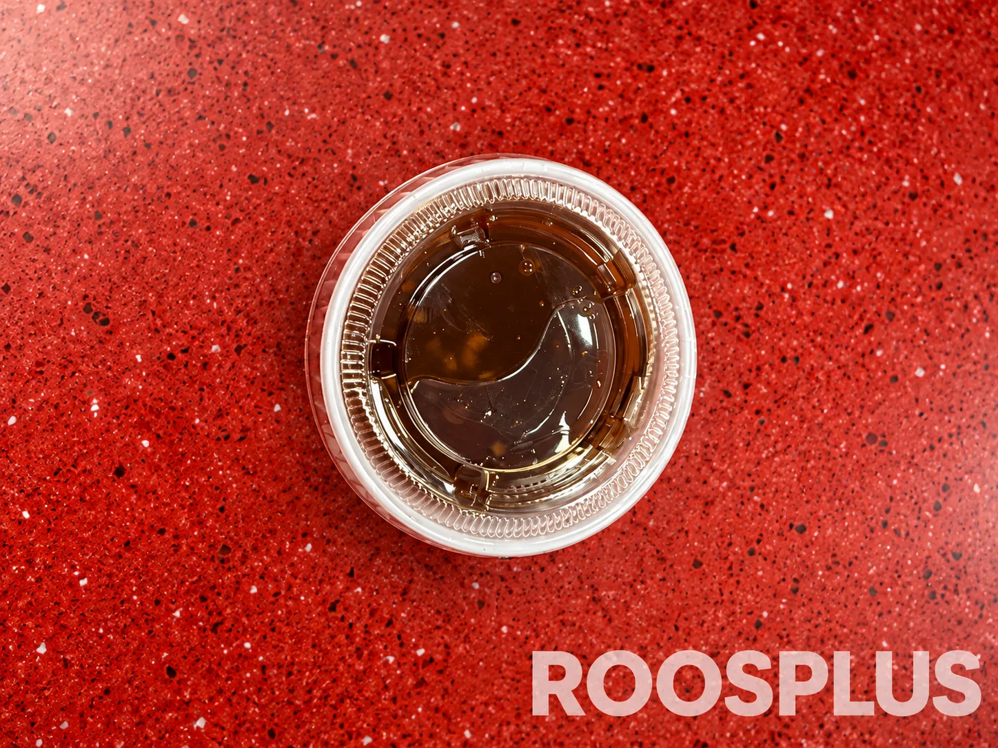 A sealed clear cup of dark brown dipping sauce at Bismillah Pizza, Eglinton Avenue East, Scarborough.