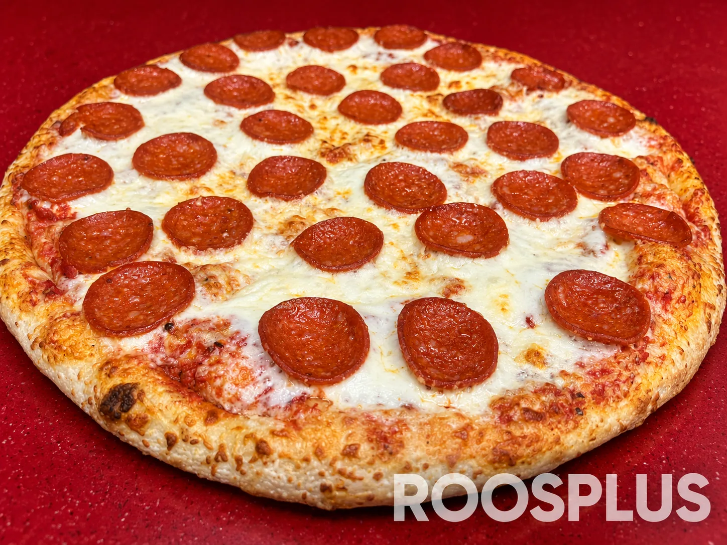 Salami pizza photographed at an angle with its golden crust in the foreground at Bismillah Pizza, Eglinton Avenue East, Scarborough.