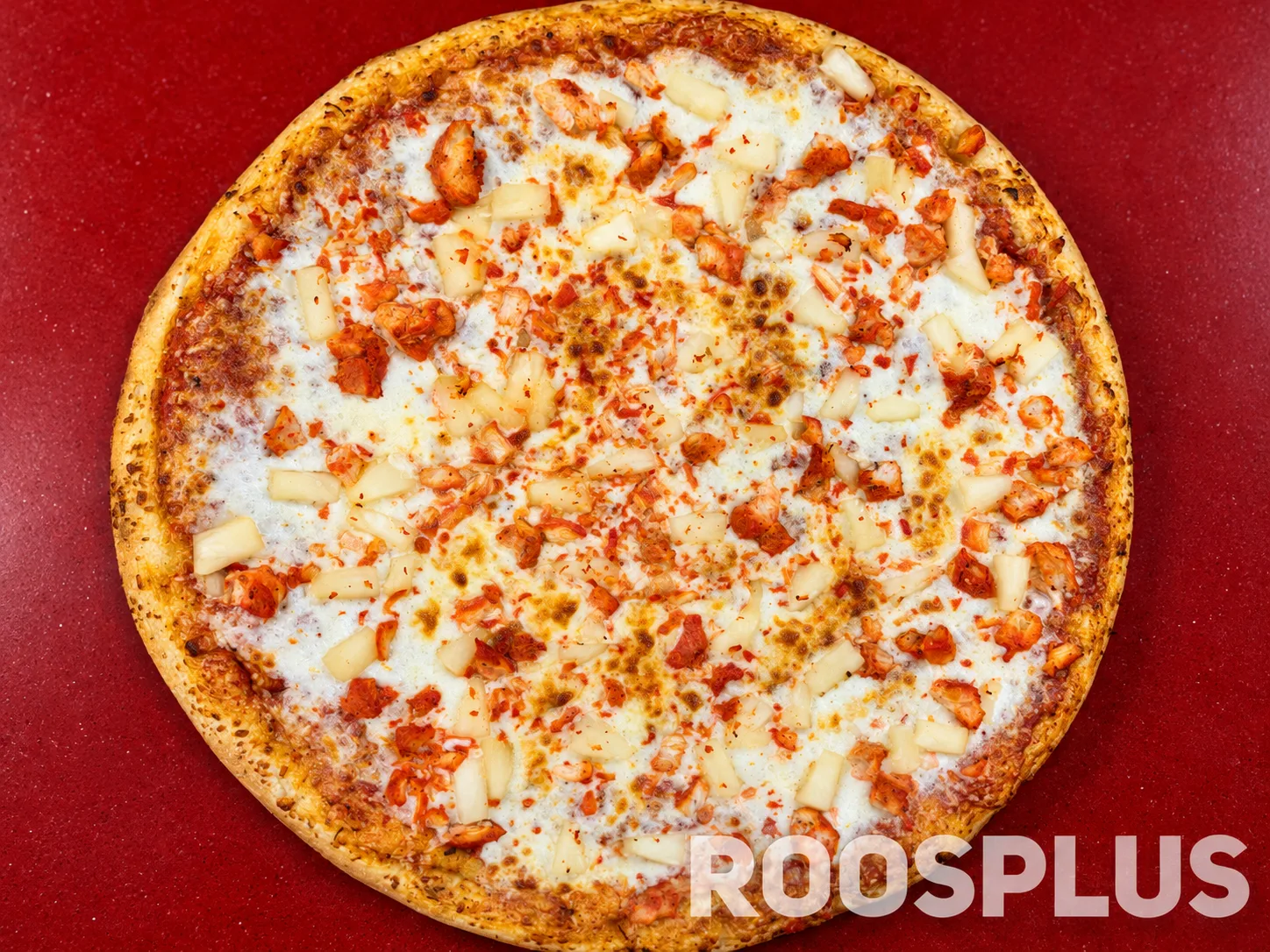 Overhead view of a cheese pizza with chicken pieces and pineapple chunks at Bismillah Pizza, Eglinton Avenue East, Scarborough.