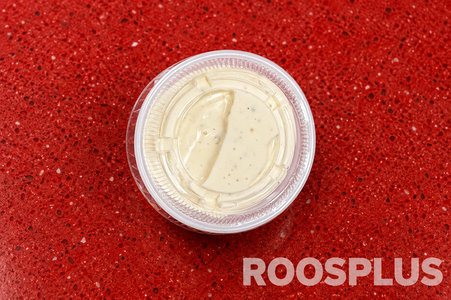 A sealed clear cup containing a pale creamy dipping sauce with seasoning flecks at Bismillah Pizza, Eglinton Avenue East, Scarborough.
