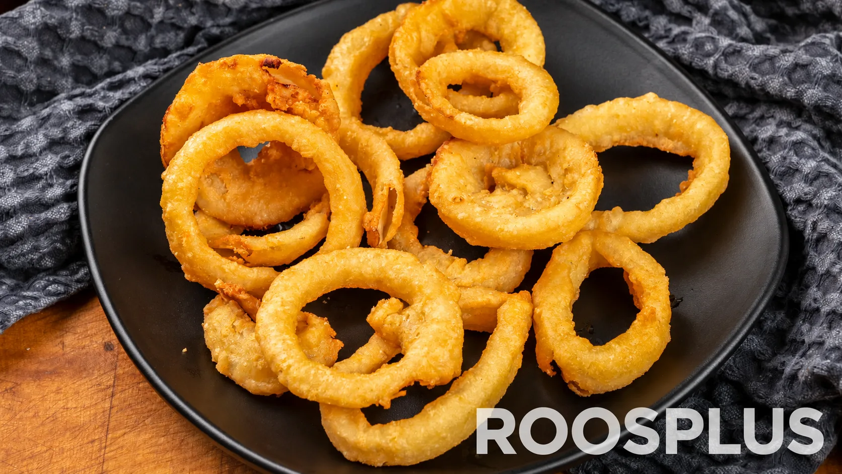 Golden battered onion rings served on a dark plate at Bismillah Pizza, Eglinton Avenue East, Scarborough.