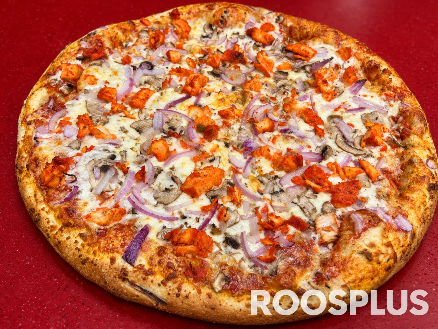 Pizza topped with tandoori chicken pieces, sliced mushrooms and red onion at Bismillah Pizza, Eglinton Avenue East, Scarborough.
